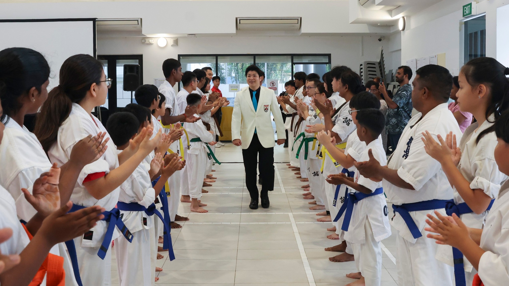 Sensei walking through a line of bowing, clapping students